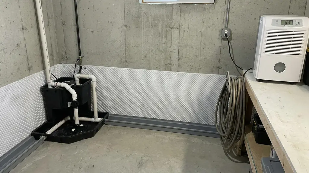 Basement wall with waterproofing membrane and sump pump system installed